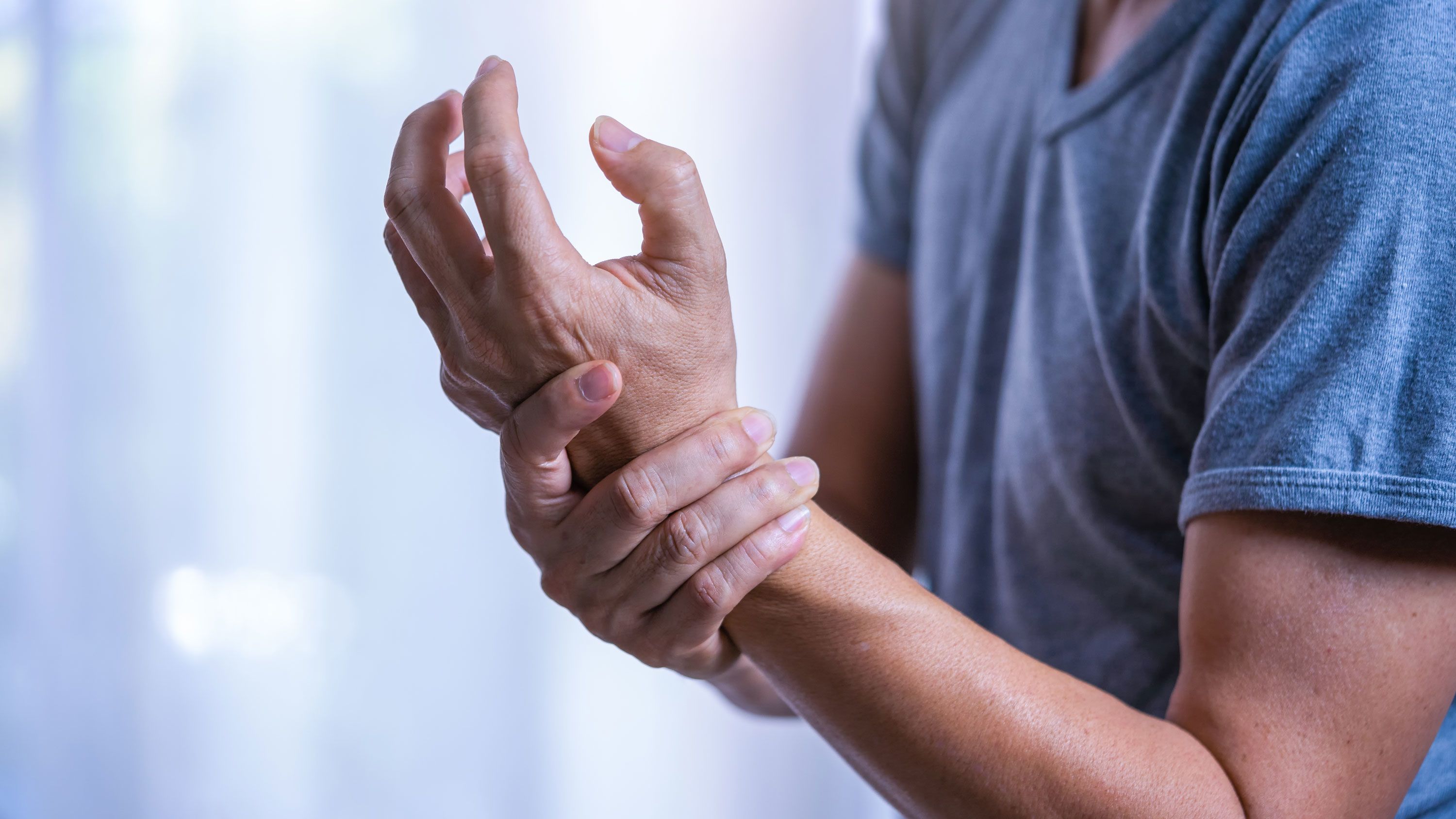Person holding their left wrist with their right hand